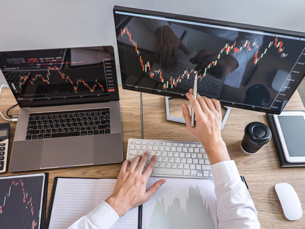 Trader analyzing stock charts on multiple screens